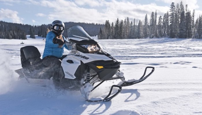 Snowmobile Photo Experience the thrill of winter adventure with this captivating photo of a woman confidently riding a snowmobile. Dressed in winter gear, including gloves, helmet, and snow goggles, she skillfully navigates the snowy terrain. The forest forms a picturesque backdrop, and snow blows dynamically from the snowmobile as she speeds through the winter wonderland.